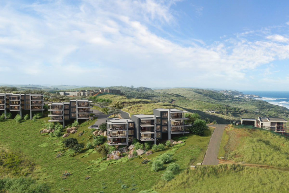 An aerial perspective of a modern coastal apartment development featuring multi-level residential blocks integrated into the hillside landscape.