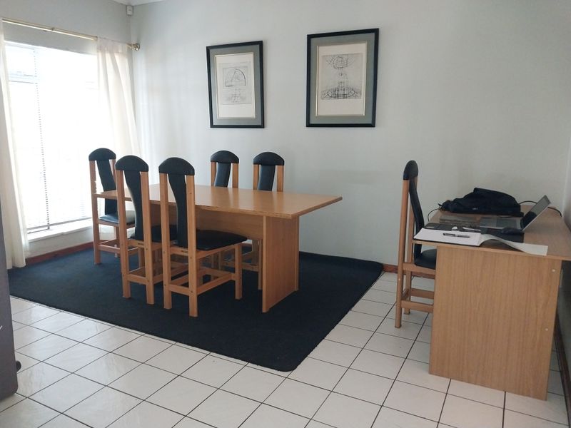 A functional dining area featuring tiled flooring and a large window, providing a bright and practical space for meals and home office use.