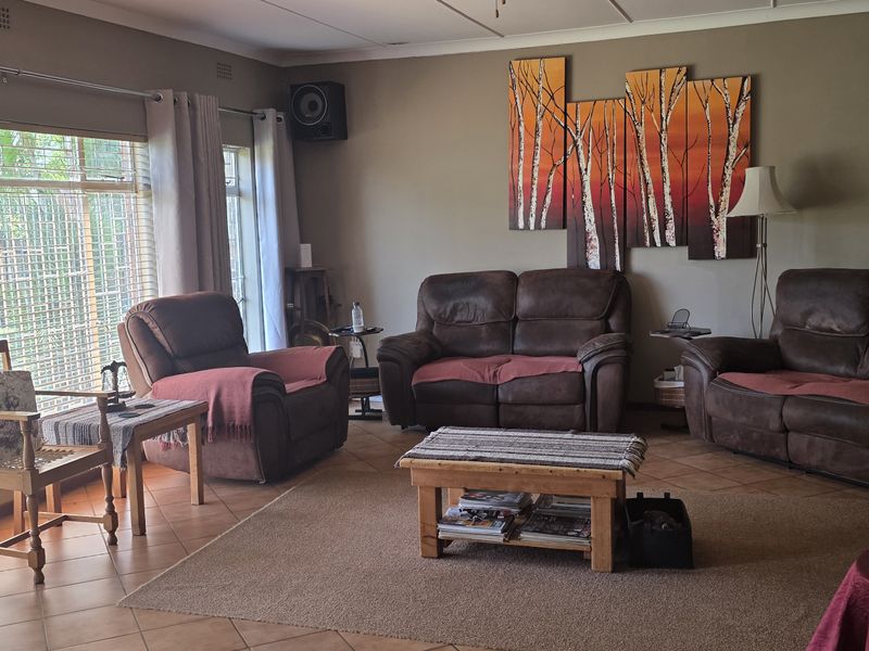 A comfortable living room featuring tiled flooring, large windows allowing natural light, and neutral wall finishes, providing a functional and inviting space.