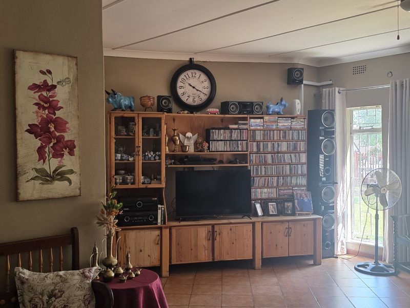 A comfortable living room featuring tiled flooring, built-in wooden cabinetry, and large windows that provide natural light and garden views.