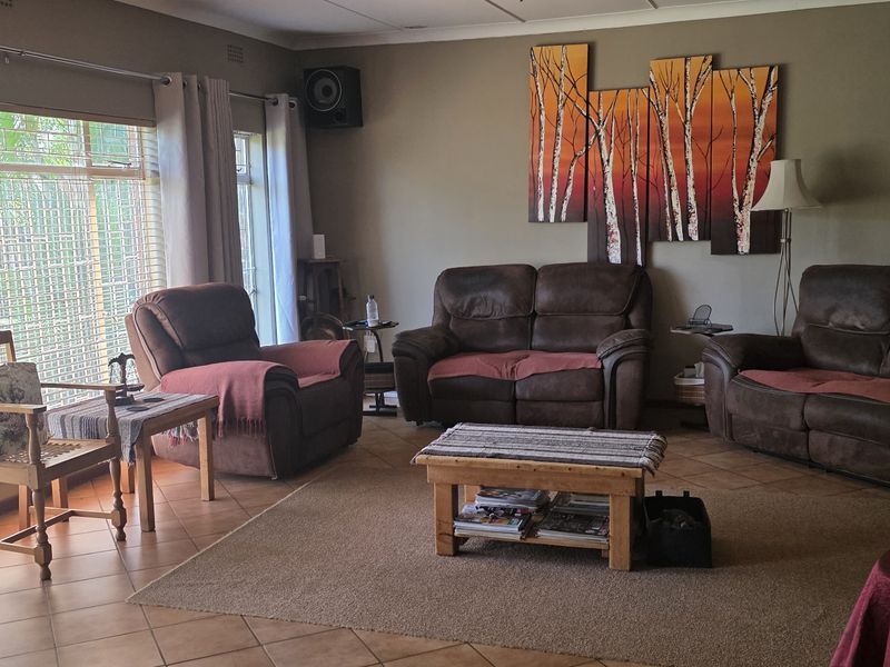 A comfortable living room featuring tiled flooring, large windows providing natural light, and neutral wall tones, offering a functional and inviting space.