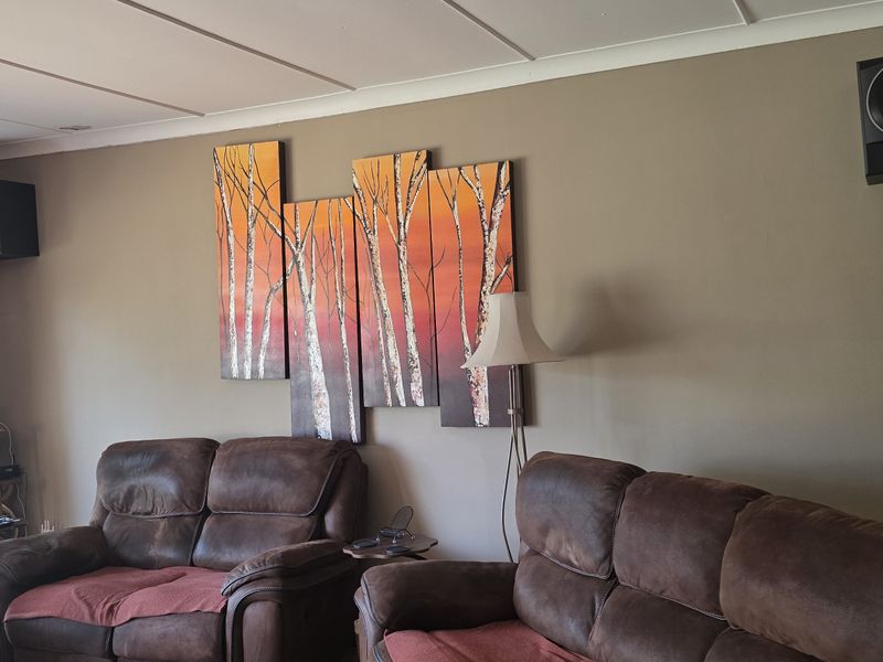 A comfortable living room featuring tiled flooring, neutral wall tones, and a window with security bars, providing a functional and inviting space.