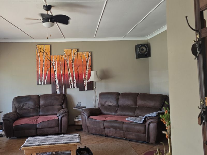 A spacious living room featuring tiled flooring, a ceiling fan, and coved ceiling details, offering a comfortable and functional living space.