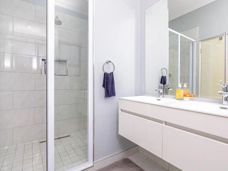 Modern bathroom featuring a spacious walk-in shower with glass enclosure and a sleek wall-mounted double vanity with large mirror.