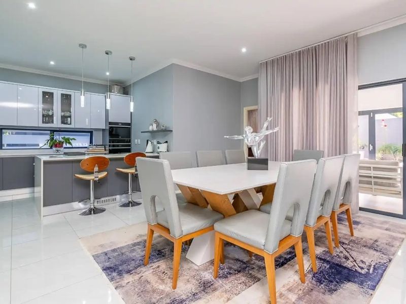 Modern open-plan living space featuring a sleek kitchen with island, dining area, and large sliding doors leading to an outdoor patio.