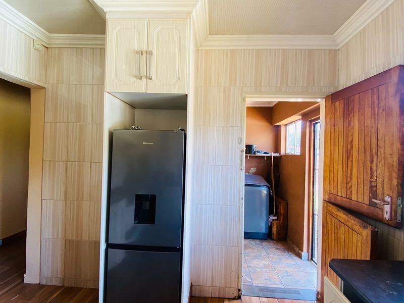 Kitchen area featuring built-in cabinetry, crown molding, and tiled finishes, with an adjacent utility space visible through the doorway.