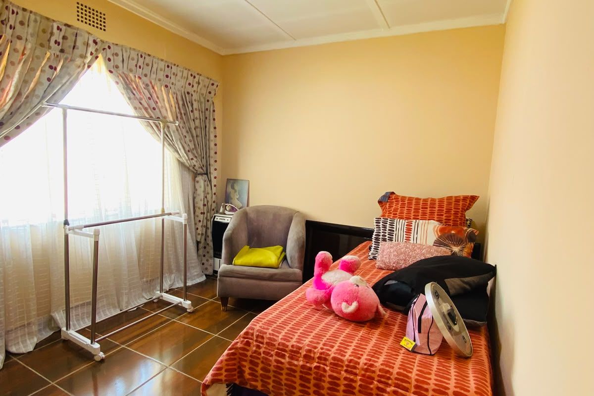 A bedroom featuring tiled flooring and a ceiling vent, requiring minor cosmetic updates to the ceiling and wall finishes.