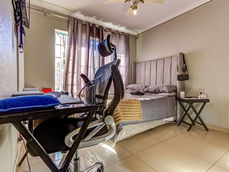 A functional bedroom featuring tiled flooring, a ceiling fan, and natural light from the window.