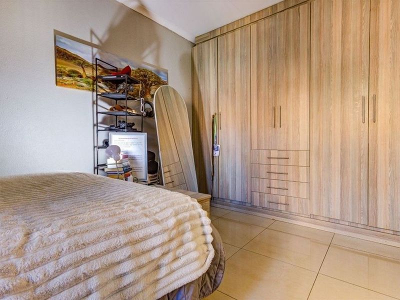 A well-maintained bedroom featuring extensive built-in wooden cabinetry and neutral tiled flooring.