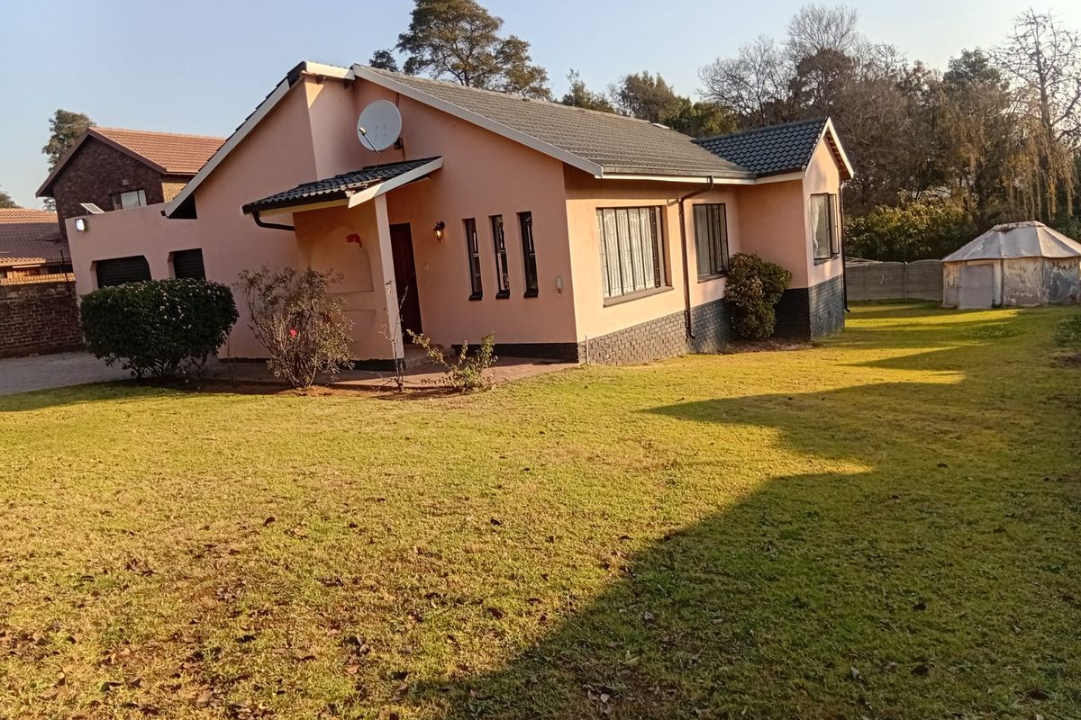 A view of the rear exterior of the house featuring a tiled roof, brick facade, and a spacious garden area.