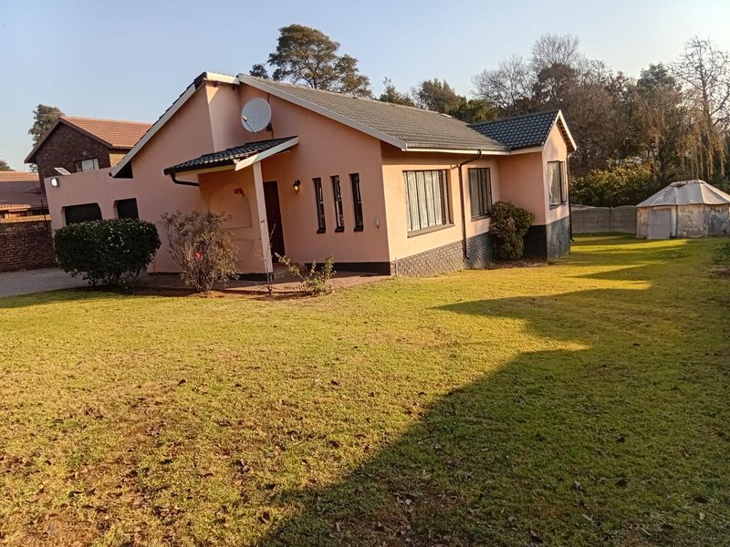 A view of the rear exterior of the house featuring a tiled roof, brick facade, and a spacious garden area.