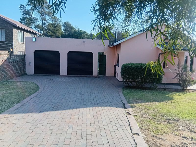 Front exterior view of the property featuring a double garage, paved driveway, and established garden area.