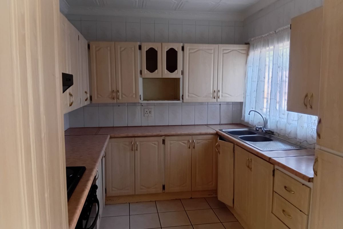 A functional kitchen featuring built-in cabinetry, laminate countertops, a double bowl sink, and tiled flooring, offering a solid foundation for a modern renovation.