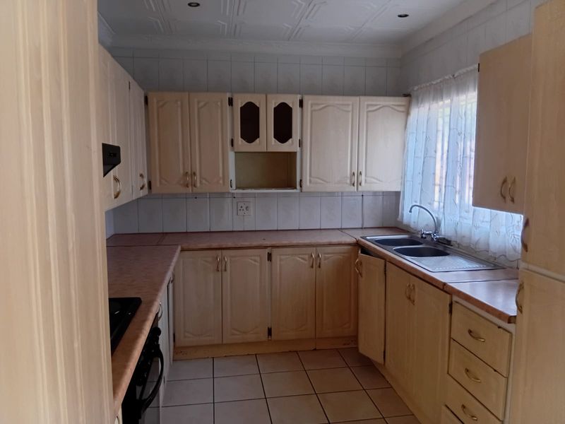 A functional kitchen featuring built-in cabinetry, laminate countertops, a double bowl sink, and tiled flooring, offering a solid foundation for a modern renovation.