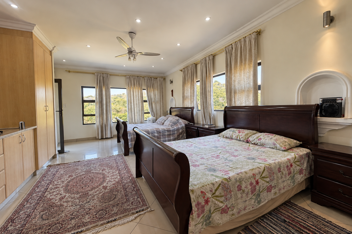 Spacious bedroom featuring built-in cupboards, tiled flooring, recessed lighting, and a ceiling fan, with large windows offering natural light and scenic views.