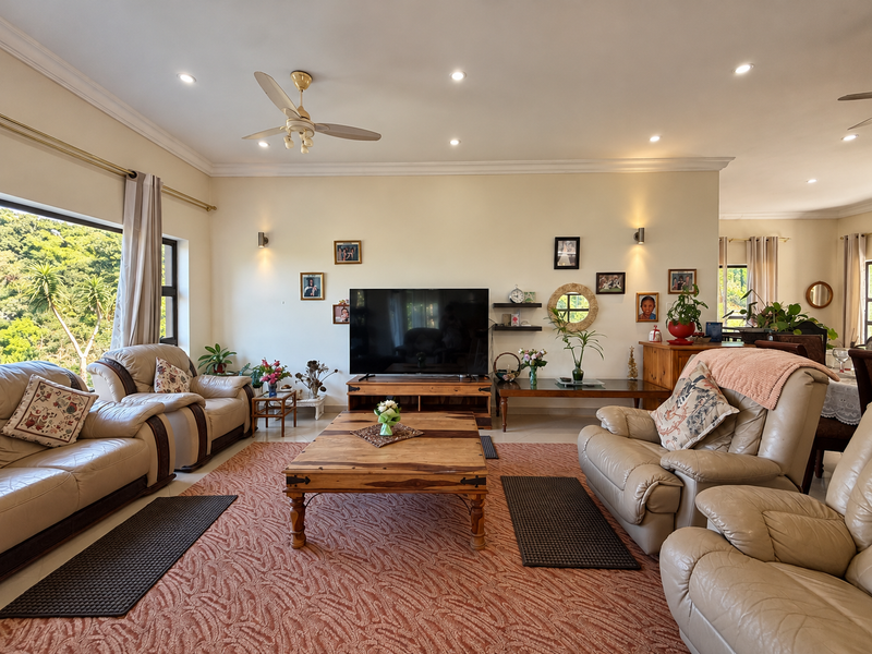 Spacious living room featuring recessed downlights, a ceiling fan, and a large window providing natural light and garden views.