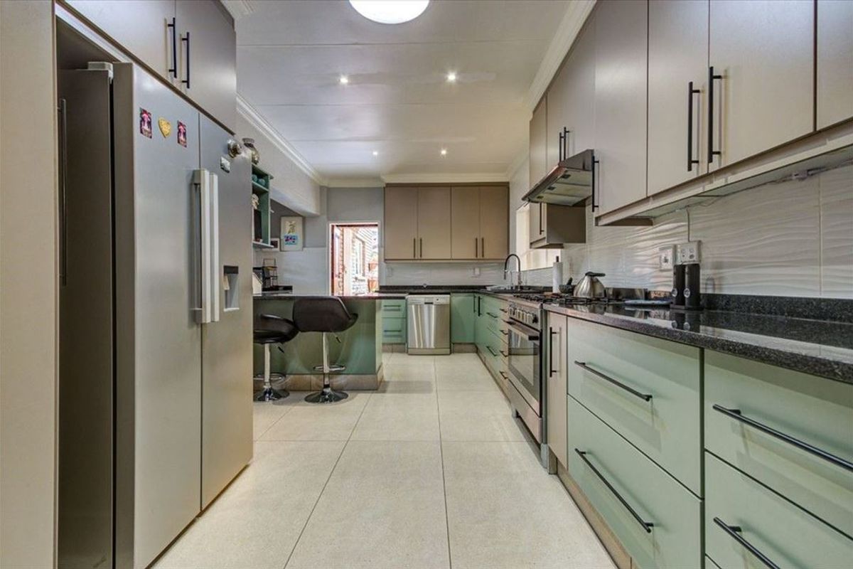 Modern kitchen featuring two-tone cabinetry, granite countertops, stainless steel appliances, and tiled flooring with recessed lighting.
