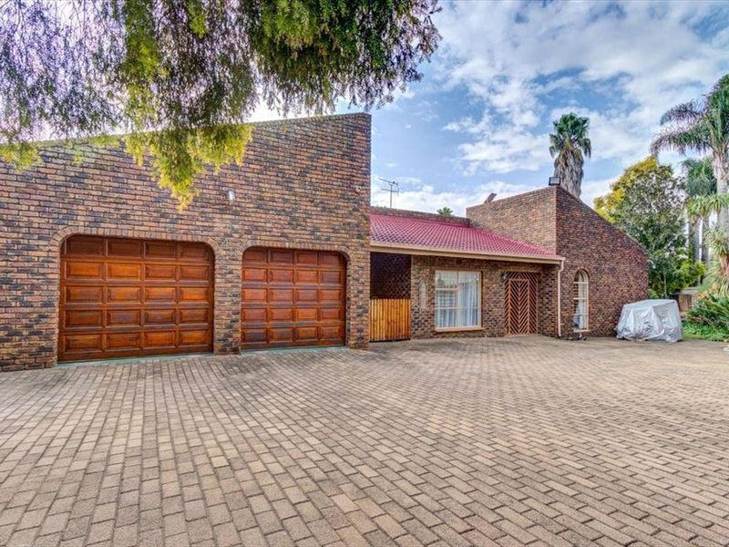 Front view of a brick-faced house featuring a double garage and an extensive paved driveway area.