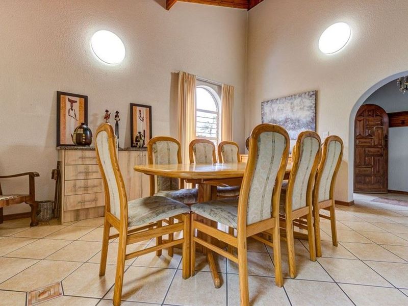 Spacious dining room featuring vaulted ceilings, tiled flooring, and an arched window, providing a bright and traditional atmosphere.