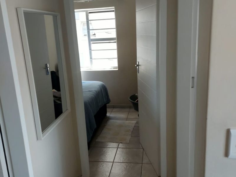 A functional hallway with tiled flooring providing access to a bedroom with a window.