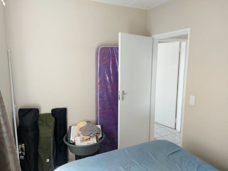 A simple bedroom interior featuring neutral wall paint and an internal door leading to an adjacent space.
