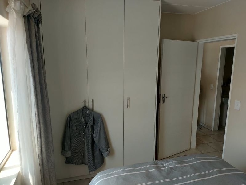 A bedroom featuring a large, white built-in wardrobe with modern handles and neutral wall finishes.