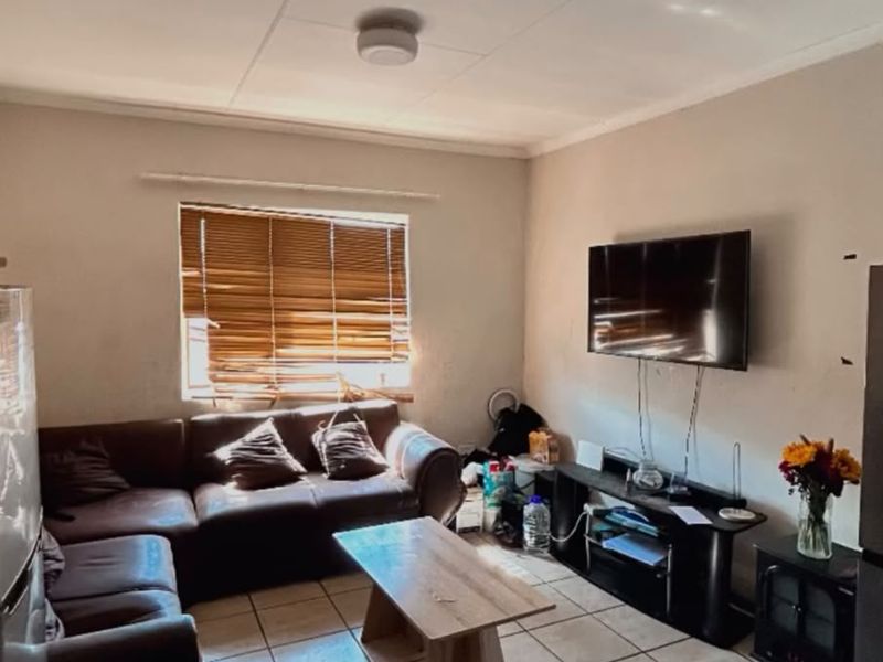 A living room featuring tiled flooring and venetian blinds, requiring minor cosmetic updates to improve the overall aesthetic and finish.