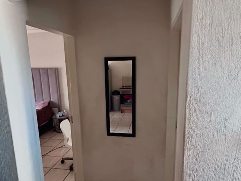 A narrow hallway featuring tiled flooring and textured wall finishes, providing access to adjacent rooms.
