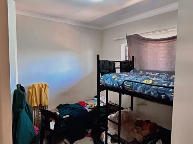 A compact bedroom featuring tiled flooring and a standard ceiling light fixture, providing a functional space for sleeping.