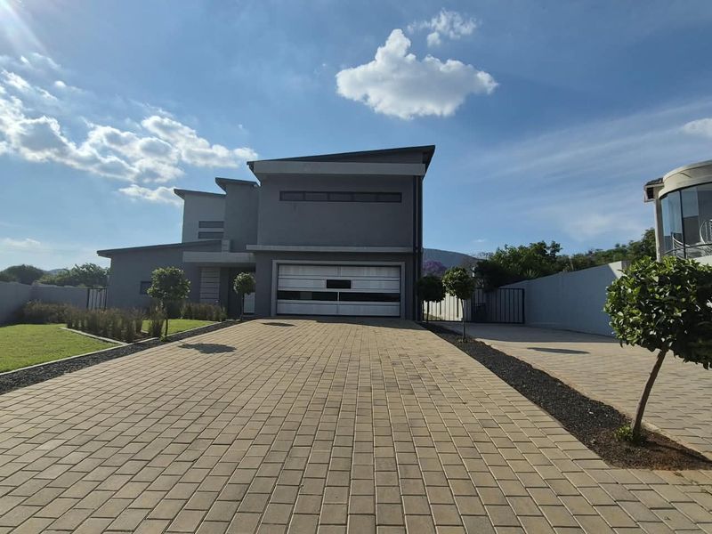 Modern double-story house featuring a paved driveway, double garage, and well-maintained front garden area.