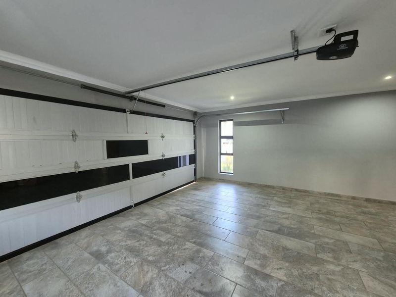 A clean, well-maintained double garage featuring tiled flooring, automated door mechanism, and recessed lighting, providing a secure and functional parking or storage space.