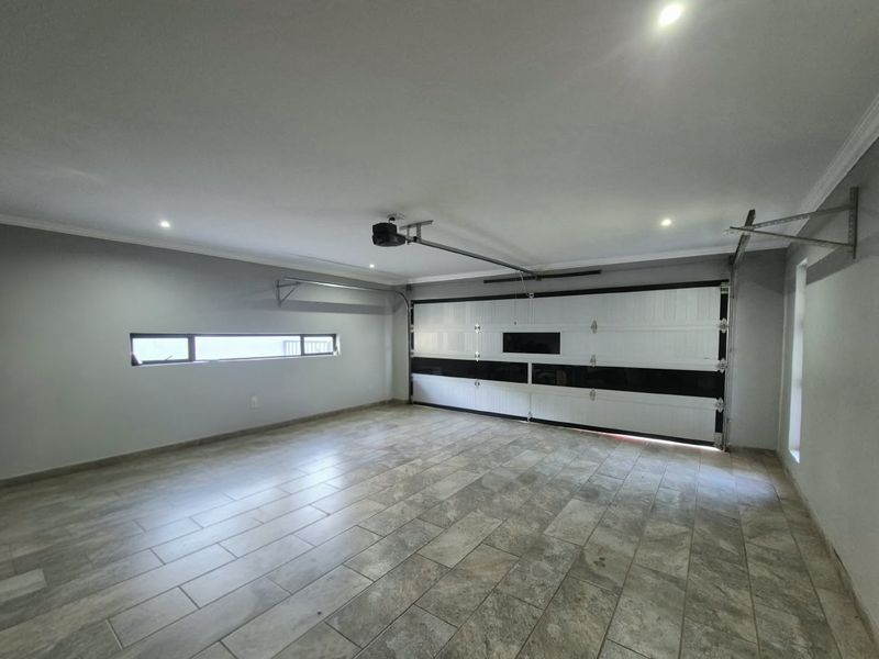 A spacious, well-maintained garage featuring tiled flooring, a modern sectional door, and recessed lighting, providing a clean and functional storage or parking space.