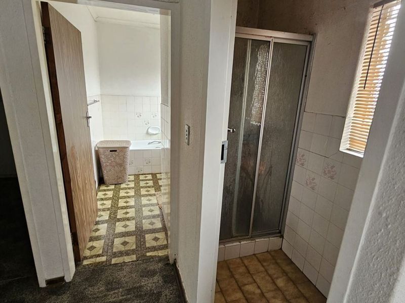 A dated bathroom featuring a separate shower and bathtub with original tiling and flooring, offering significant potential for a modern renovation.