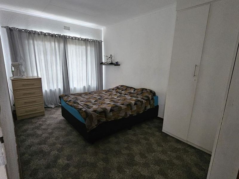 A standard bedroom featuring carpeted flooring, a built-in wardrobe, and a ceiling light fixture, offering a functional space ready for personalization.