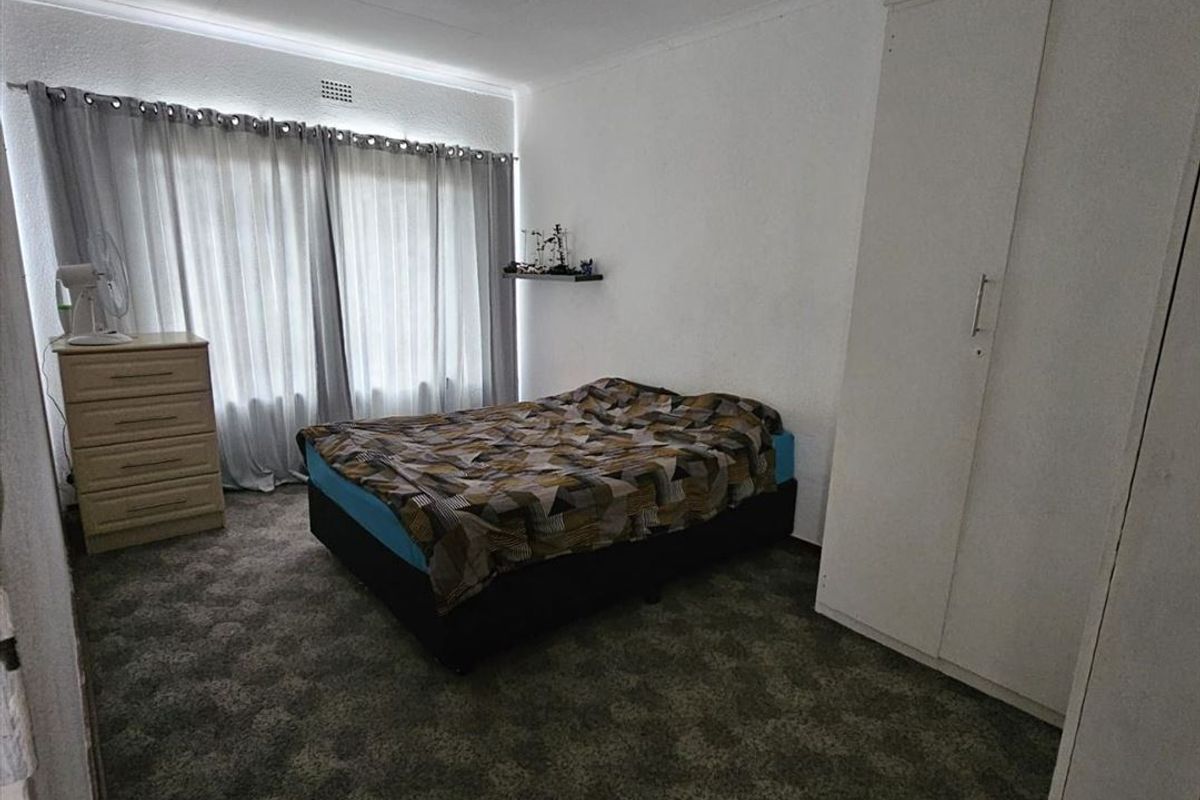 A standard bedroom featuring carpeted flooring, a built-in wardrobe, and a ceiling light fixture, offering a functional space ready for personalization.