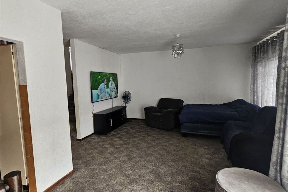 A living room area featuring neutral wall finishes and carpeting, offering a blank canvas for potential interior updates and modernization.