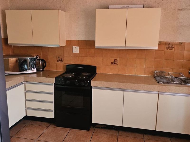 A functional kitchen featuring dated cabinetry, laminate countertops, and ceramic tile finishes, offering potential for a modern renovation.