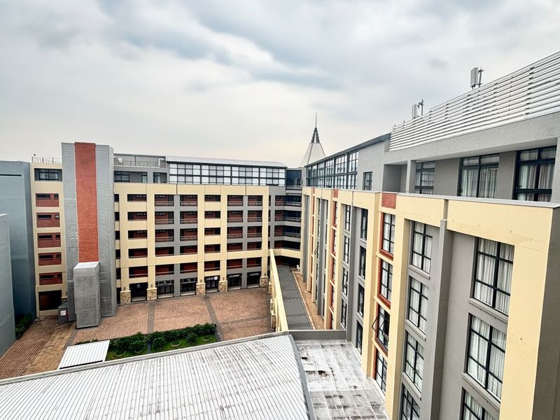 An elevated view of the apartment complex courtyard, featuring paved outdoor areas and multi-story building facades with large windows.