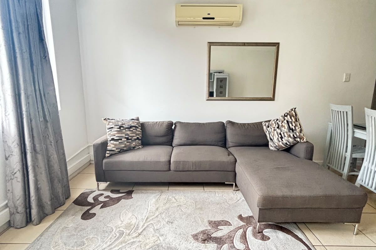 A living room featuring tiled flooring and a wall-mounted split-system air conditioning unit.