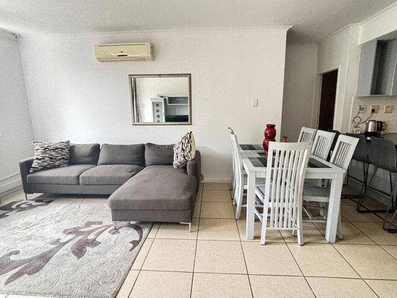 Open-plan living and dining area featuring ceramic floor tiles and a wall-mounted split-system air conditioner, seamlessly connected to the kitchen space.