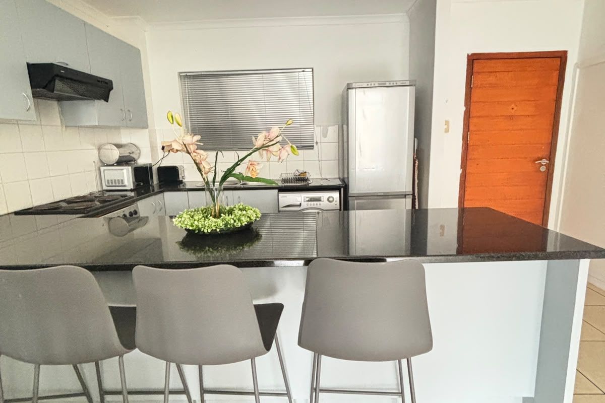 A functional kitchen featuring a granite breakfast bar, built-in cabinetry, tiled flooring, and recessed lighting, offering a practical layout for daily use.