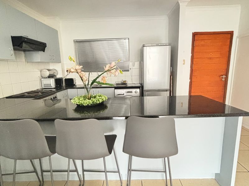 A functional kitchen featuring a granite breakfast bar, built-in cabinetry, tiled flooring, and recessed lighting, offering a practical layout for daily use.