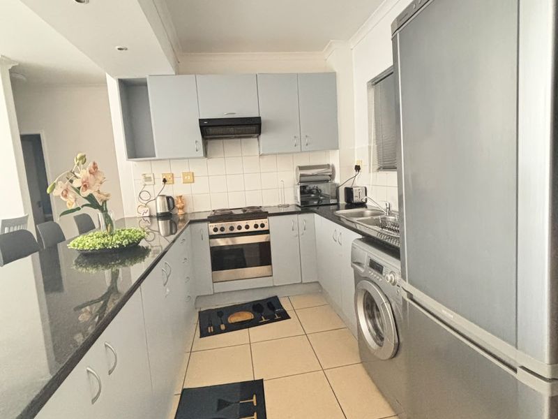 A functional kitchen featuring built-in cabinetry, granite countertops, a built-in oven with hob, and tiled flooring with a practical layout.