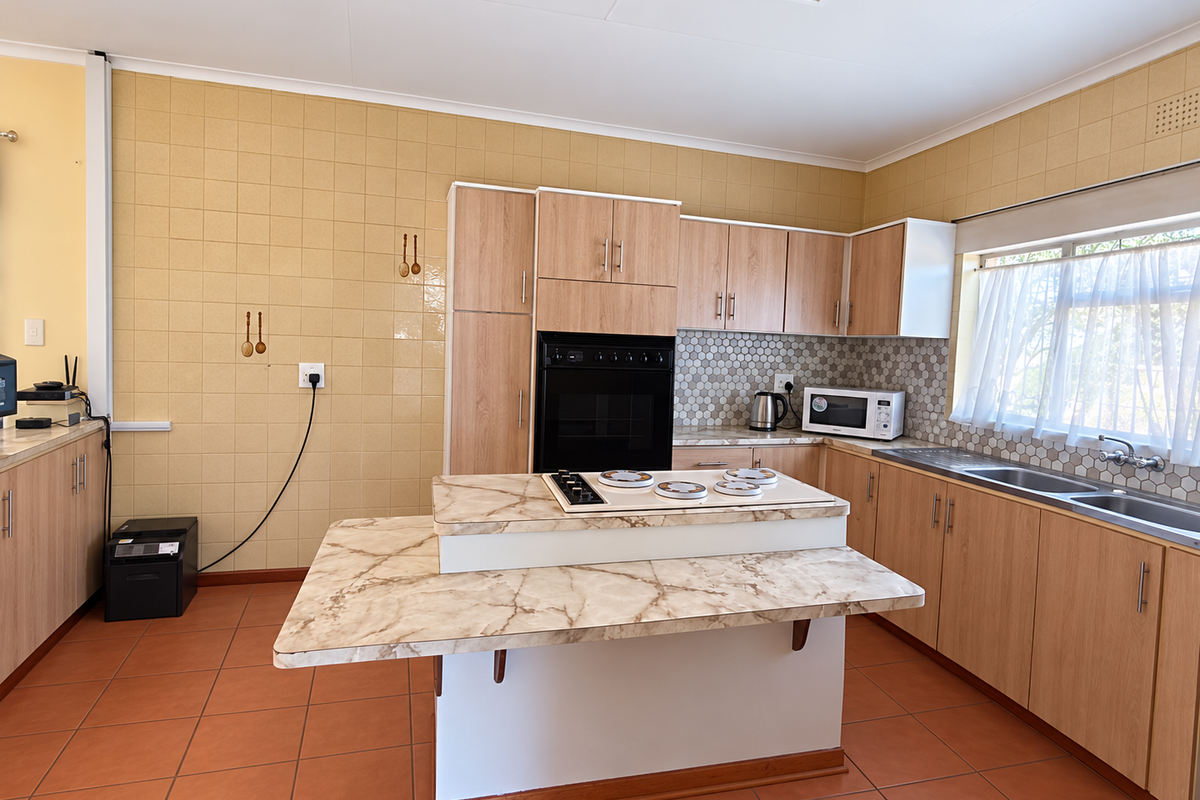 A functional kitchen featuring light wood cabinetry, marble-look laminate countertops, a built-in oven and hob, and tiled flooring throughout.