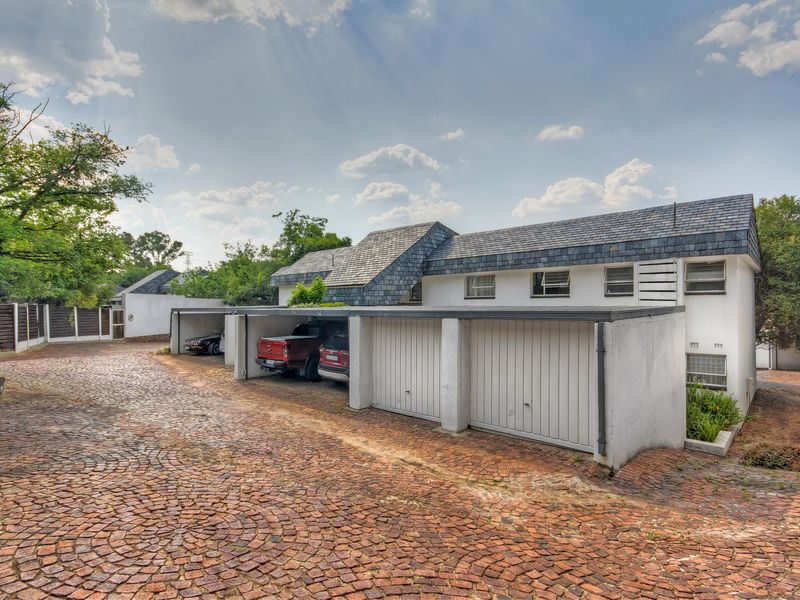 Exterior view of a townhouse complex featuring a cobblestone driveway and multiple garage bays with slate roof detailing.