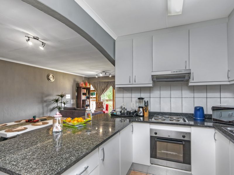 Open-plan kitchen featuring granite countertops, built-in oven, and hob, seamlessly flowing into the adjacent living and dining area.