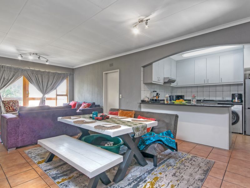 Open-plan living and dining area featuring tiled floors, an arched kitchen pass-through, and functional kitchen cabinetry with granite countertops.
