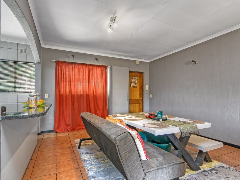 Open plan dining area featuring tiled flooring, a granite breakfast bar, and direct access to the kitchen area.
