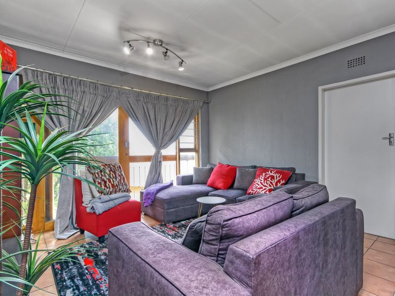 A comfortable living room featuring tiled flooring, modern track lighting, and a sliding glass door providing access to the exterior.