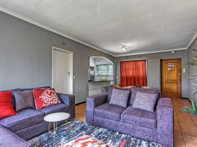 Open plan living area featuring tiled flooring, an arched kitchen pass-through, and direct access to the main entrance.